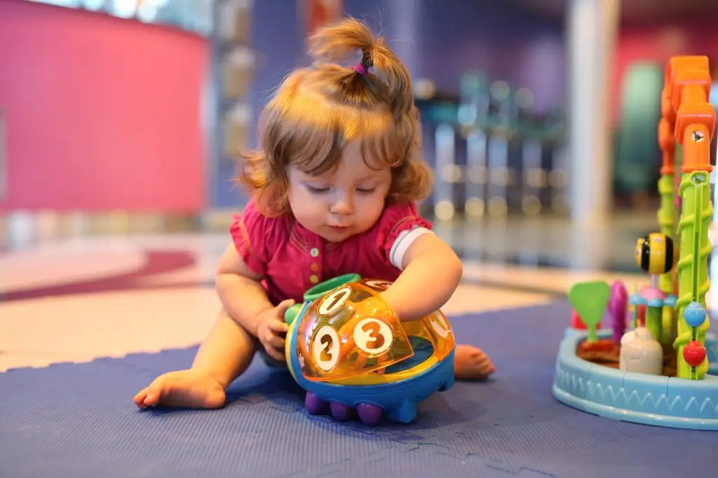 Baby girl playing with toys in a playroom of cruise liner